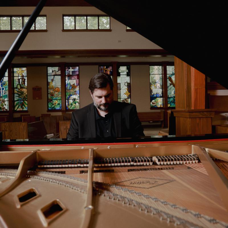 Shot of Bradley, deep in thought at the piano, taken from the rear of the piano, with the strings exposed